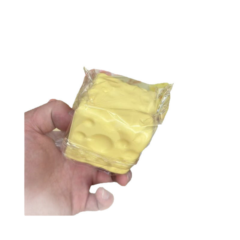 Single cheese cube squishy sealed in clear film, moulded round holes visible through it