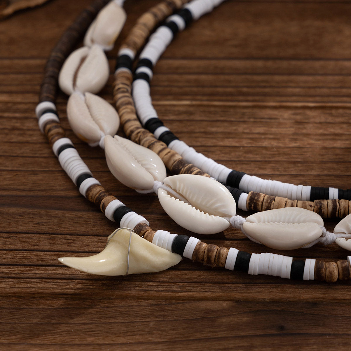 Macro of the cowrie shells knotted on white cord beside the cream tooth shaped pendant