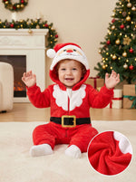 Baby sitting by a Christmas tree wearing the red fleece Santa hooded jumpsuit with beard collar and belt