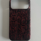 Dark red and black snake print half-cover phone case on a grey surface, Dark Mamba, iPhone 16 option