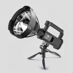 Black portable LED searchlight standing on its folding tripod bracket with USB charging handle