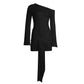 Black bodycon mini dress on a white background, front view with slanted shoulder, bell sleeves and knot tail