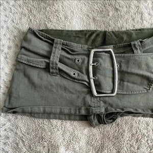 Army green buckle mini skirt shown from the front on a soft blanket