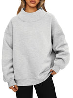 Woman in a light gray oversized mock neck sweatshirt with black leggings, front view