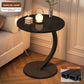 Pure black round top side table with a black steel C frame and disc base beside a bed, option Pure Black