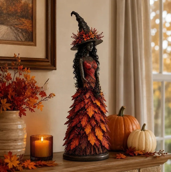 Orange variant: witch statue with red bodice and orange leaf gown on a mantel with pumpkins