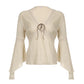 Front flat view of the cream blouse, ladder tapes tracing the empire seam and the elbow of each sleeve