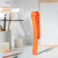 Single vibrant orange silicone bookmark clip standing on a desk beside a pen cup