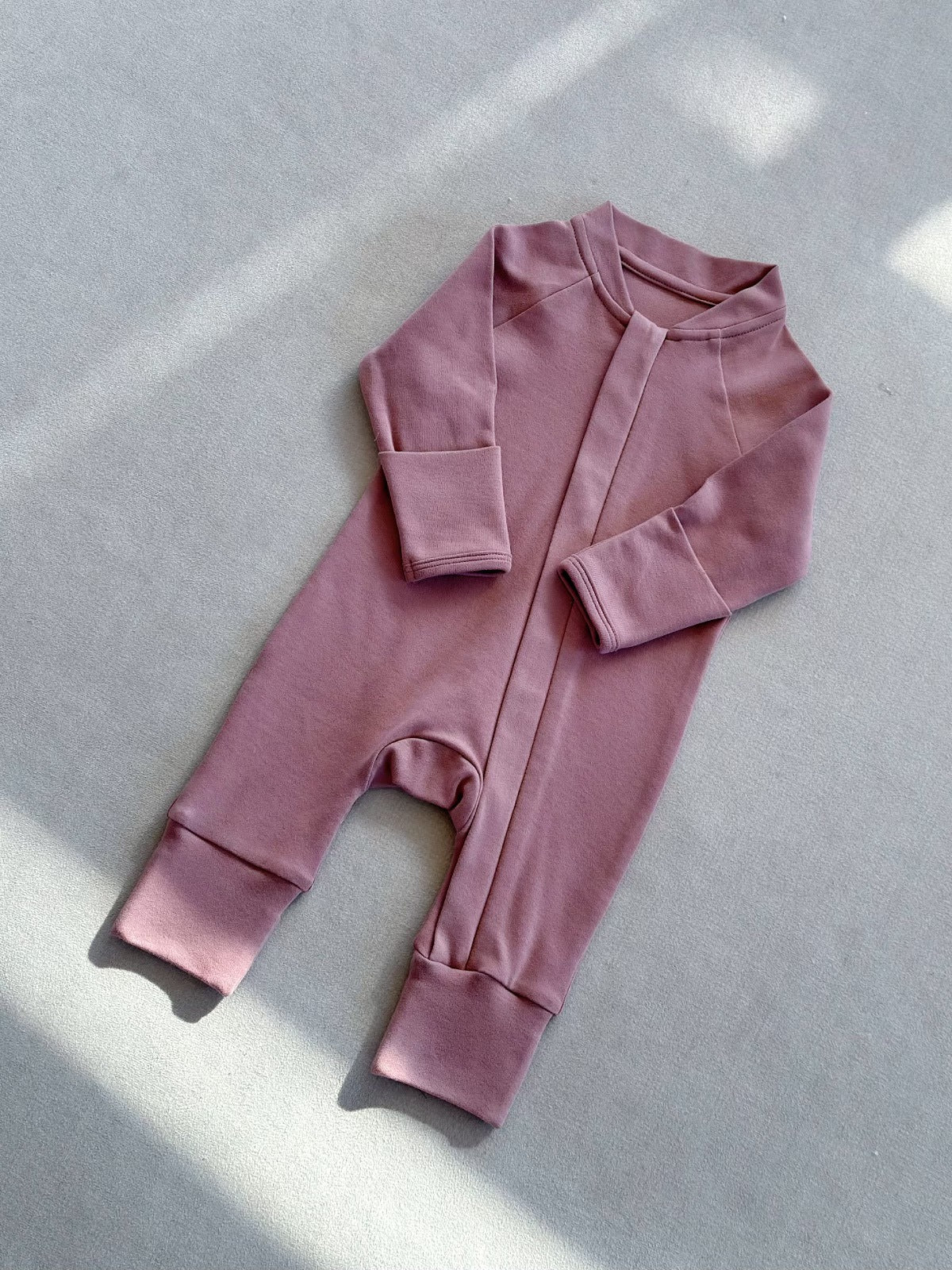 Rose Pink zip front baby romper laid flat on a gray floor, image of the 59 cm, 0 to 3 months size option