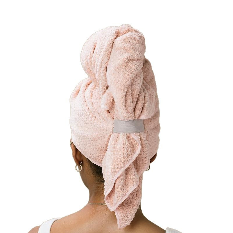 Pink hair towel wrapped around the head and secured with a grey elastic strap, back view
