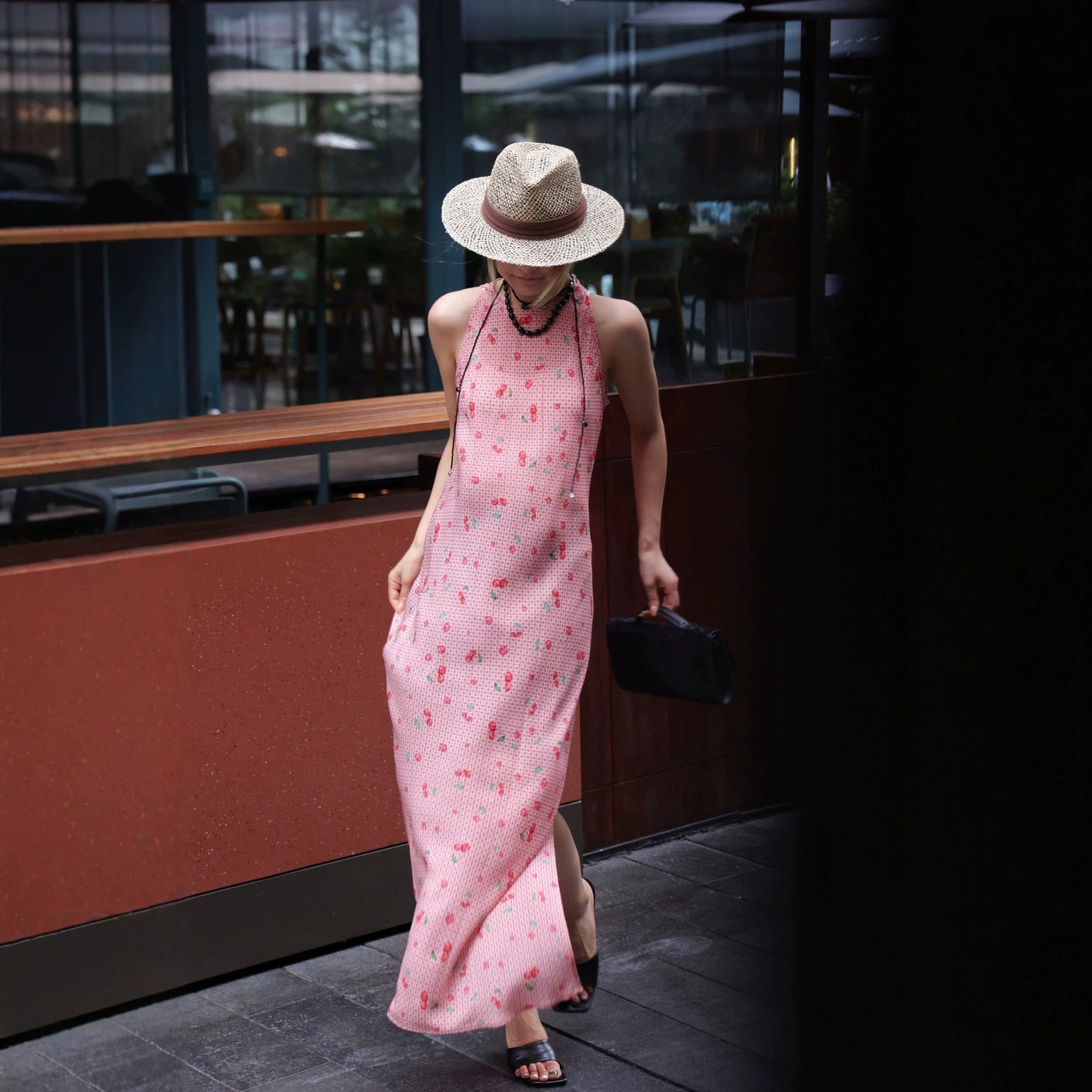 Pink cherry gingham silk halter maxi dress worn walking with a straw hat