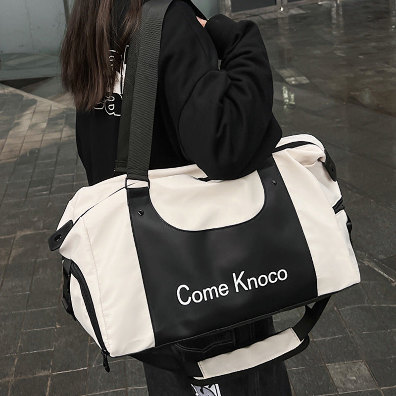 Black and white duffle gym bag with Come Knoco lettering carried on the shoulder on a wet city street