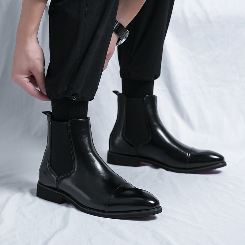 Black leather Chelsea ankle boots with cap toe and elastic side panels worn with black trousers and socks