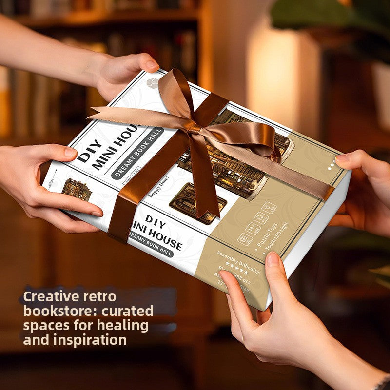 Boxed DIY Mini House Dreamy Book Hall wooden model kit held in two hands as a wrapped gift