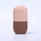 Black ribbed silicone facial ice tool standing tall on a pale grey background