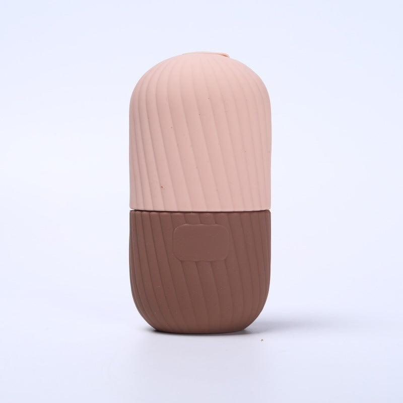 Black ribbed silicone facial ice tool standing tall on a pale grey background