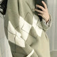 Woman in a matcha green argyle knit sweater with cream diamonds, side view in front of a mirror