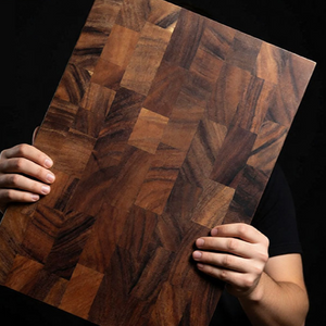 Solid walnut end grain cutting board held up to show its checkerboard block face