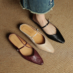 Beige, wine red and black leather pointed toe mules lined up on a woven mat