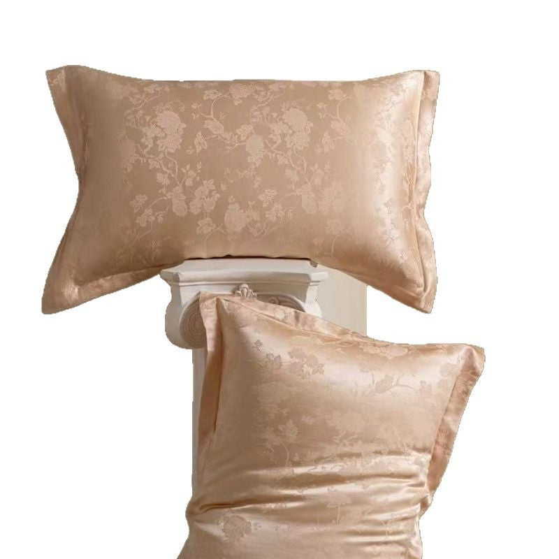 Pair of peach floral jacquard silk pillowcases, one flat and one on a column, on a white background