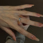 Adjustable silver cubic zirconia ring worn across the finger, small shoulder accents beside the round center stone