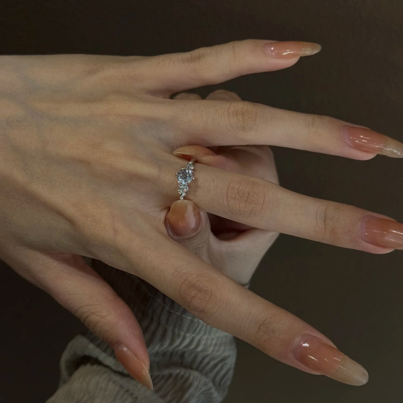 Adjustable silver cubic zirconia ring worn across the finger, small shoulder accents beside the round center stone