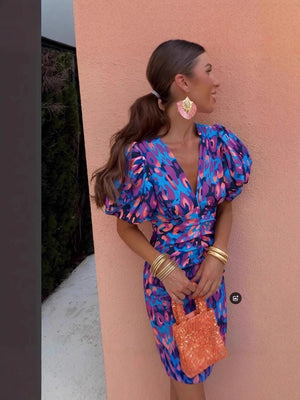 Blue animal print V-neck puff sleeve bodycon dress worn against a warm terracotta wall