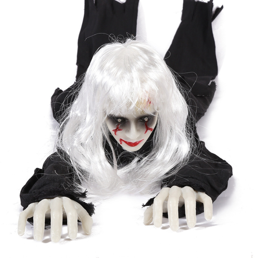 White-haired female ghost prop in tattered black clothes crawling forward with pale plastic hands, front view