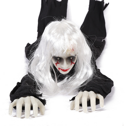 White-haired female ghost prop in tattered black clothes crawling forward with pale plastic hands, front view