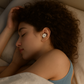 Front view of beige flat-profile Bluetooth sleep earbuds for side sleepers