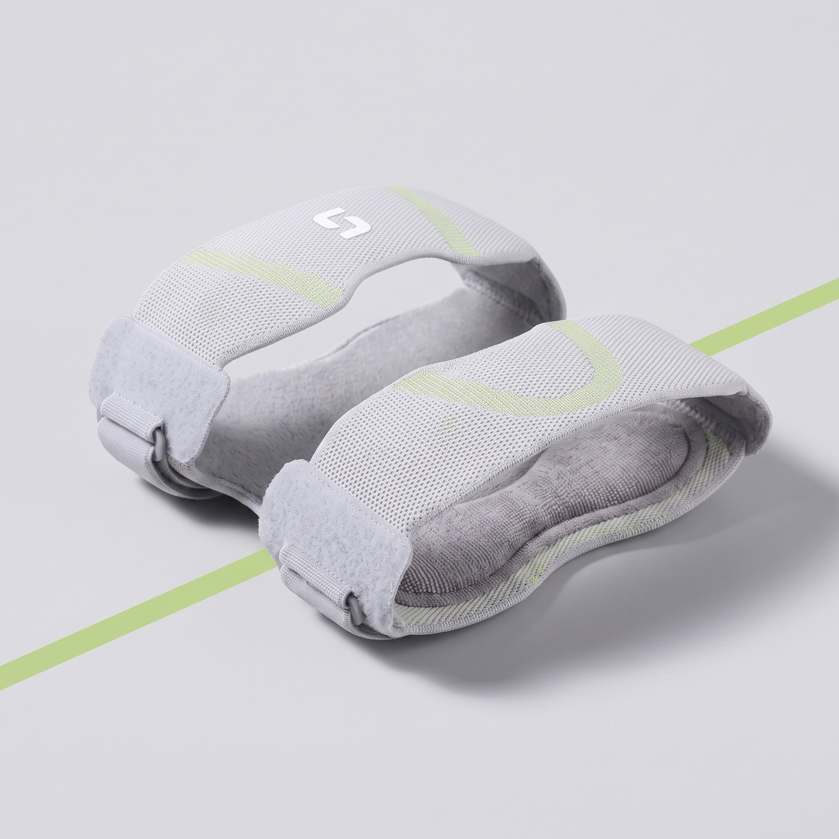 Studio view of the light cloud grey two band knee support with green wave knit and grey velcro straps