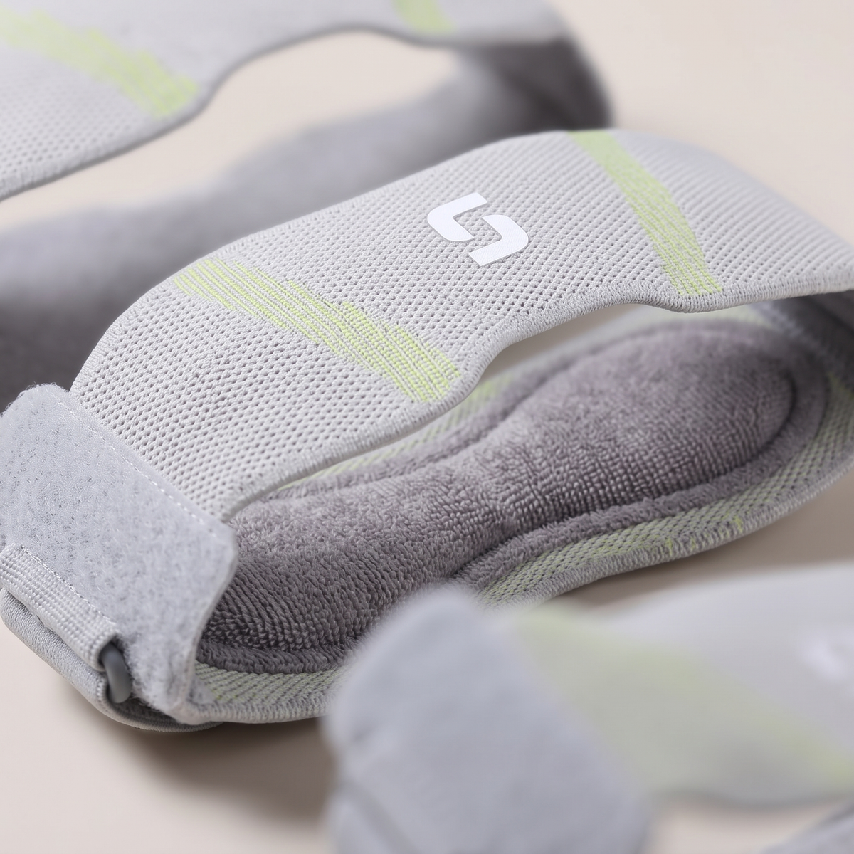 Close view of the seamless grey knit, green wave, white logo, grey velcro strap and inner towel lining