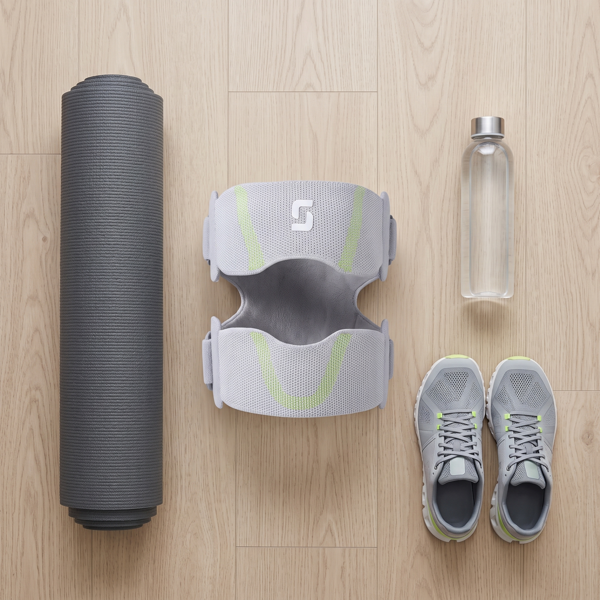 The two band knee support laid out with a yoga mat, water bottle and running shoes