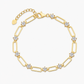 Gold loop chain bracelet laid flat on a marble surface in window light