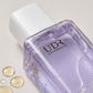 Close up of the UDR body essence oil bottle showing golden oil droplets beside it
