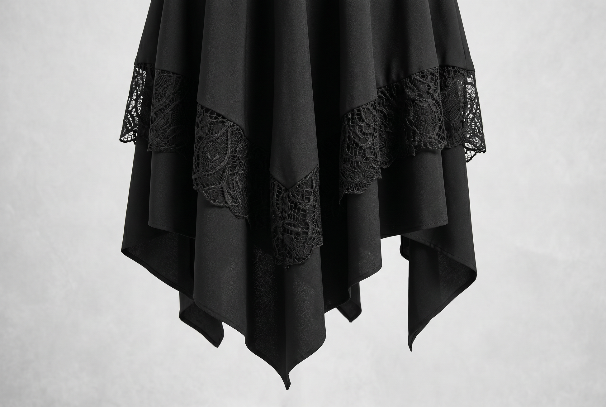 Close macro of the black asymmetrical pointed hem skirt with dark lace trim panels and layered handkerchief points