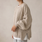 Side angle of the knitted sweater showing puff sleeve volume, ribbed cuff and side slit