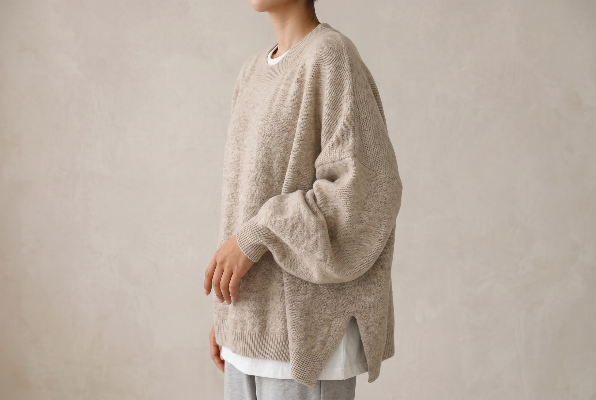 Side angle of the knitted sweater showing puff sleeve volume, ribbed cuff and side slit