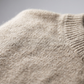Close up of the soft heathered oatmeal knit and ribbed edge of the sweater