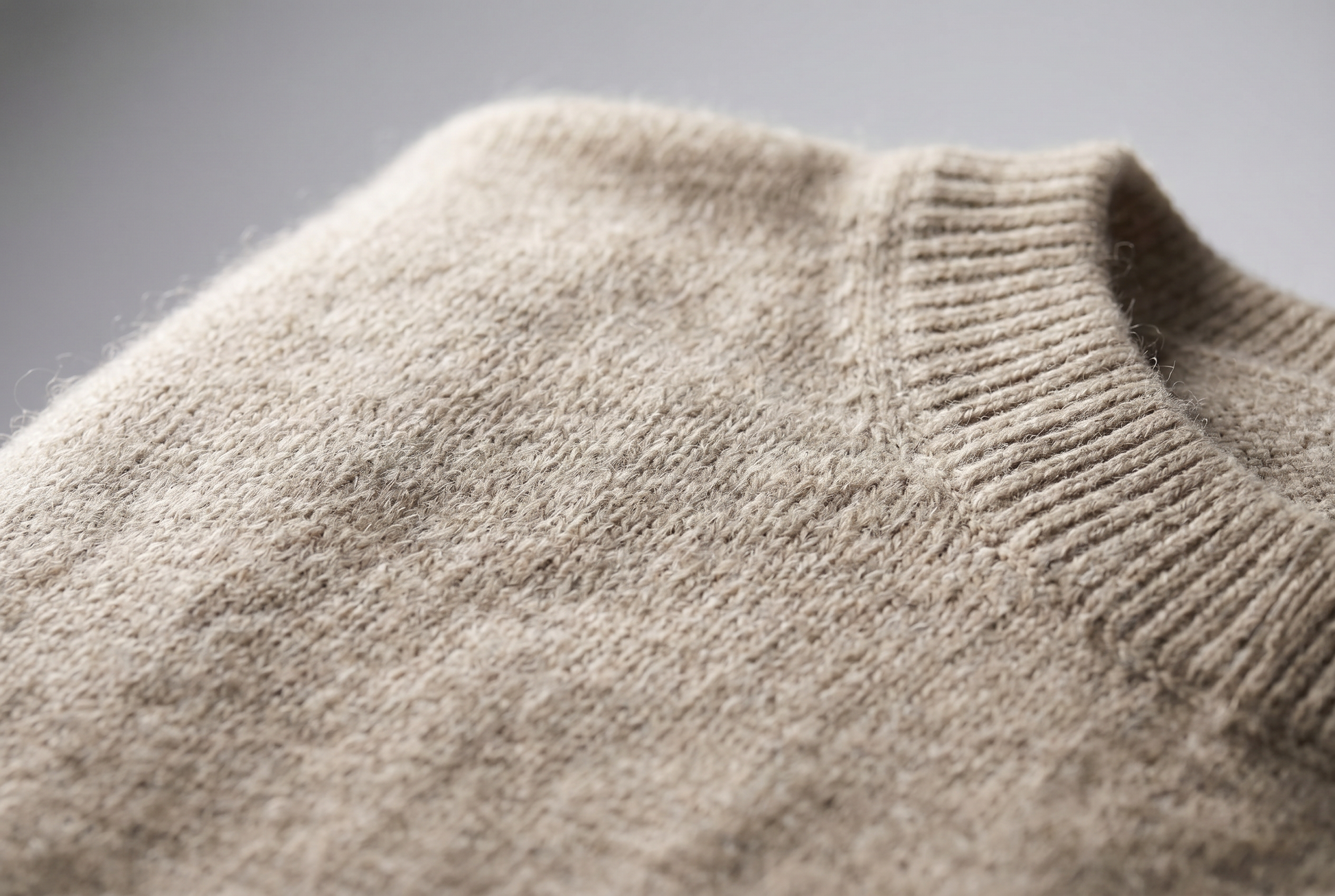 Close up of the soft heathered oatmeal knit and ribbed edge of the sweater