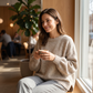 Woman relaxing at a cafe wearing the oatmeal knitted puff sleeve sweater