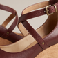 Close up of the burgundy cross strap, brass rivet and gold buckle on the chunky heel sandal