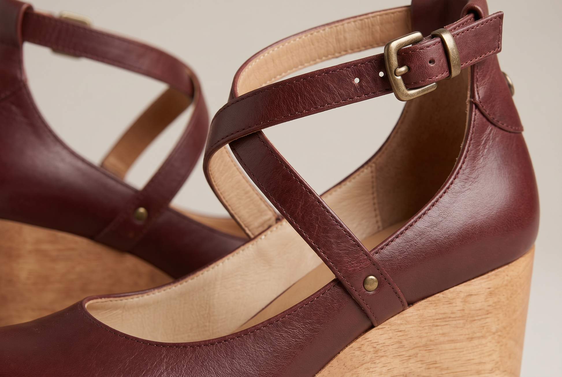 Close up of the burgundy cross strap, brass rivet and gold buckle on the chunky heel sandal