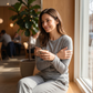Same cafe scene before wearing the knitted sweater, in a plain thin top feeling the chill