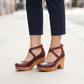 Woman standing on a pavement wearing the burgundy cross strap chunky heel sandals