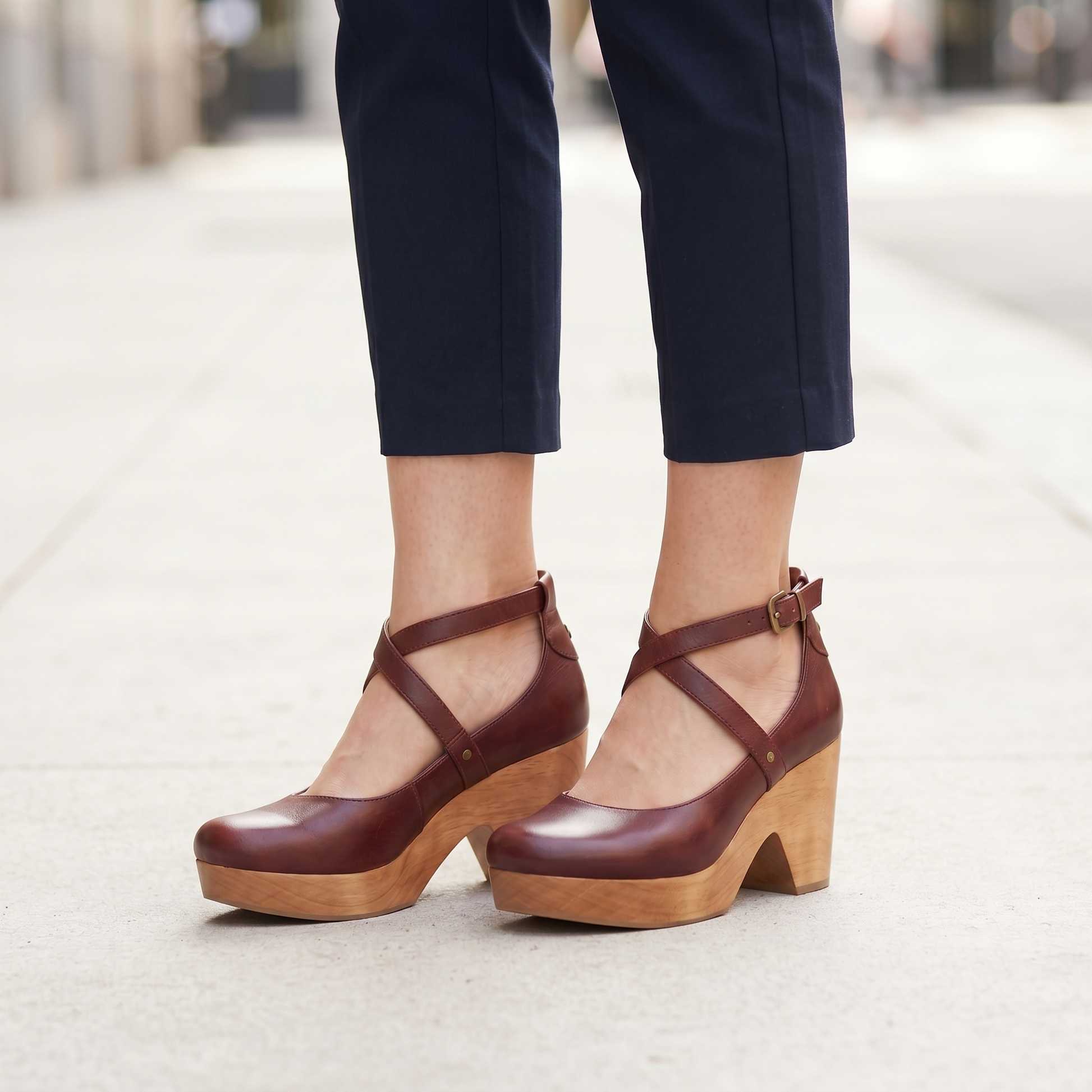 Woman standing on a pavement wearing the burgundy cross strap chunky heel sandals