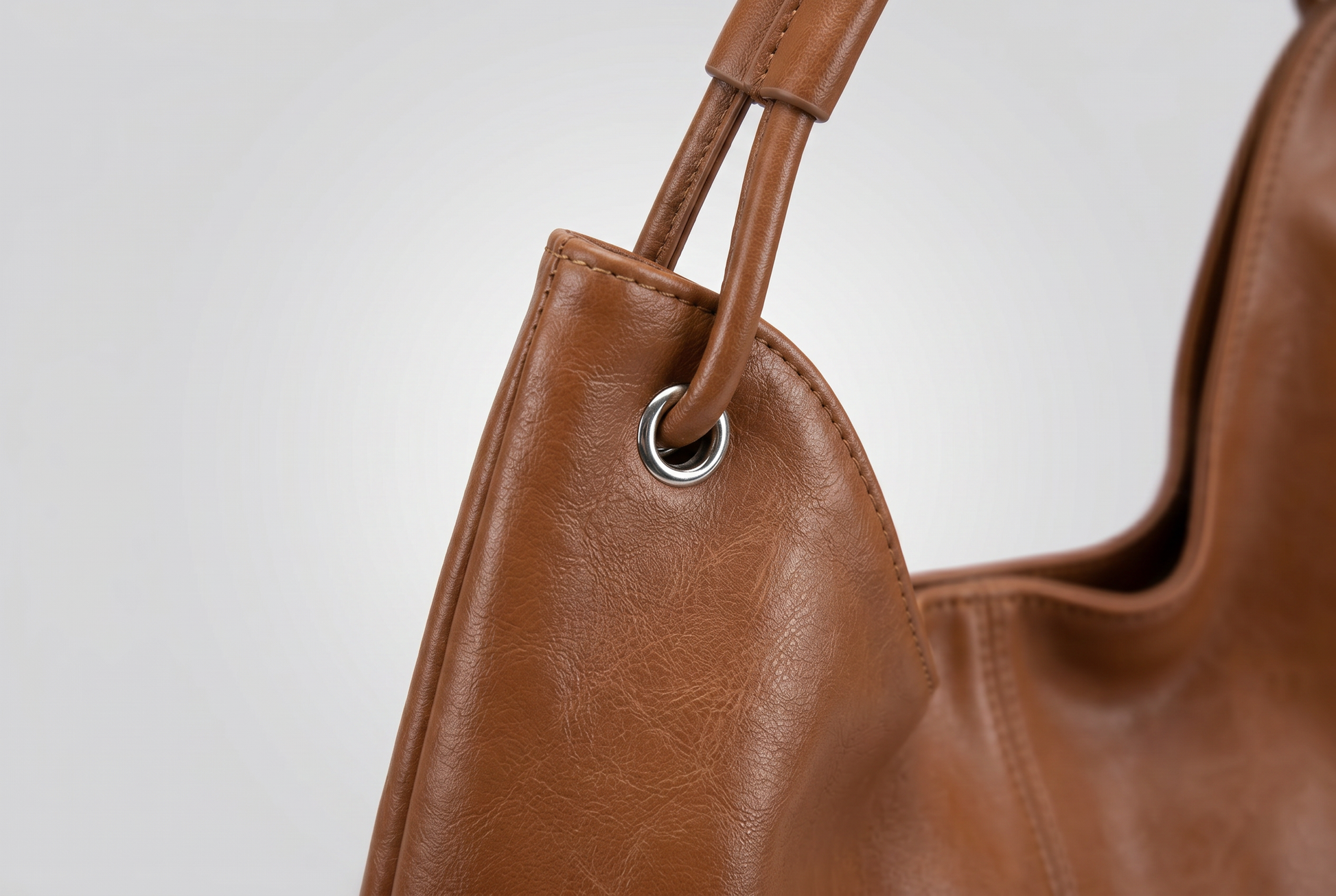 Close up of the walnut leather grain and the strap threaded through the silver eyelet