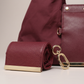 Close up of burgundy leather mini pouch charm with gold lobster clasp and metal bar