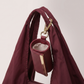 Burgundy leather mini pouch charm clipped to the handle of the nylon tote open top view