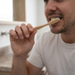 A person brushing teeth with a soft bristled bamboo toothbrush